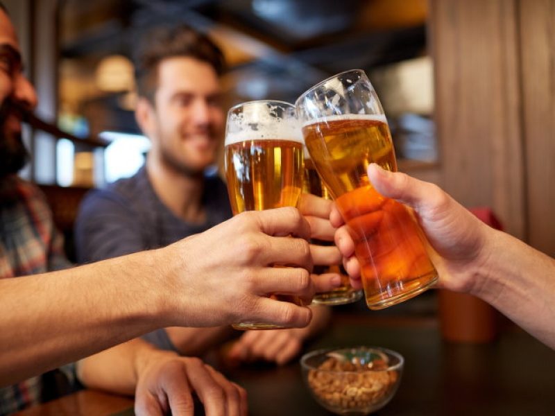 people, men, leisure, friendship and celebration concept - happy male friends drinking beer and clinking glasses at bar or pub